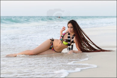 African Light Skinned Curvy Model In Bikini With Long Braided Hair Laying Down On Dubai Beach Full